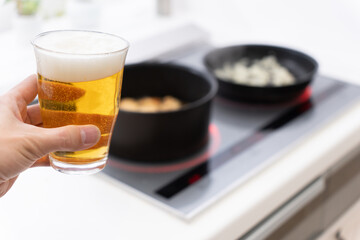 キッチンで料理をしながらビールを飲む男性