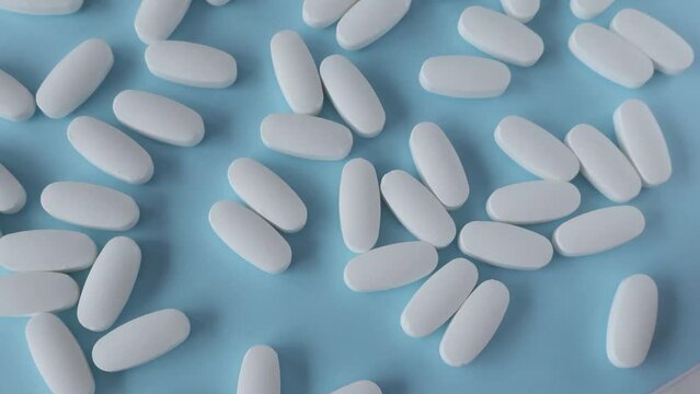 L glutamine white oval tablets scattered on a blue background, view from above