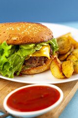 Homemade imperfect burger with potatoes and salad on a plate. Food on the table in a white plate on a wooden board