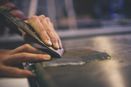 A carpenter sharpens the blade of a hand planer.