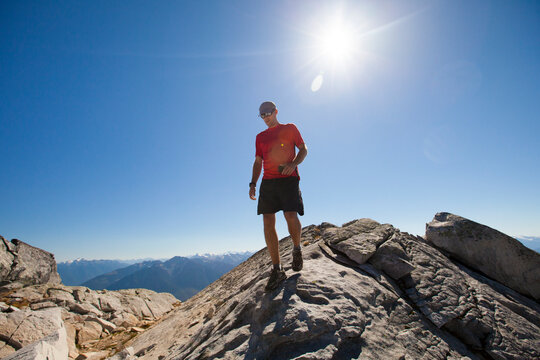 A hiker walks along a rocky ridge while on the summit of Cassiope Peak near Pemberton, British Columbia, Canada.