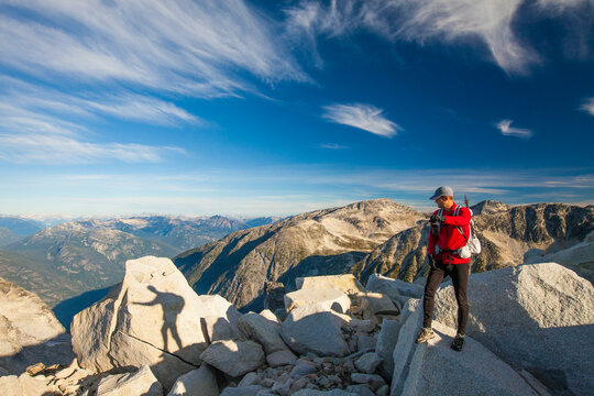The shadow of a ultralight backpacker is projected on a large granite rock high in the rocky mountains of British Columbia, Canada.