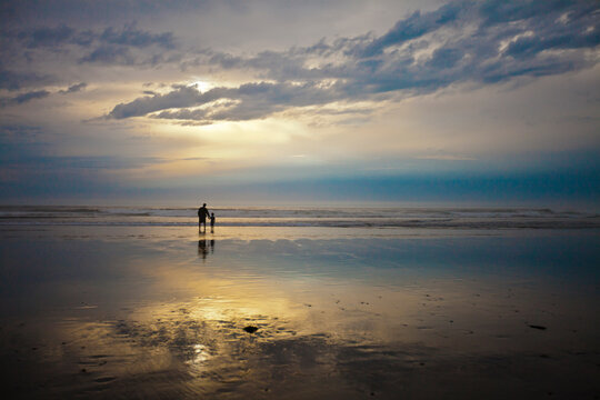 A father and son watch the sunset while vacationing at Rockaway Beach, Oregon.