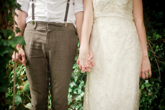Mid-section of a bride and groom holding hands at a simple wedding ceremony.