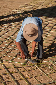 A Thai Man Prepares A Grid Of Cut Bamboo Poles Prior To Pouring A Concrete Pad In Pai, Thailand