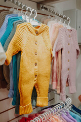 Bright spring jumpsuits for newborns hang on hangers in a children's clothing store