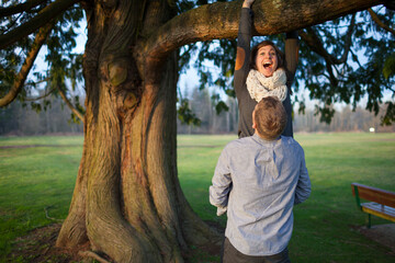 Couple climbing tree at park