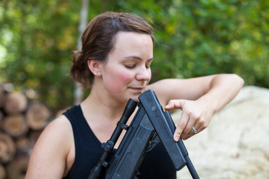 A woman looks down the barrel of a breeched rifle