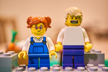 Fototapeta premium Lego girl figurine with glasses standing next to a man that is scared