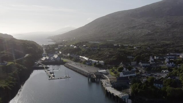 Dynamic drone shot of the village of Tarbert on a sunny day, featuring the Isle of Harris Distillery. Filmed on the Isle of Harris, part of the Outer Hebrides of Scotland.