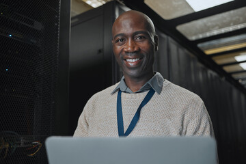 Laptop, portrait and IT black man in server room for research, engineer working in dark data center...