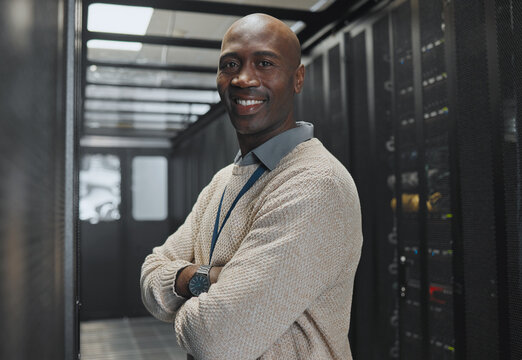 Black man, IT technician in server room and portrait with smile, company mainframe and software update. Network, datacenter and cybersecurity. African male and engineering with digital infrastructure - Powered by Adobe