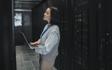 Server room, laptop and young woman or technician in data center management, system and cyber...