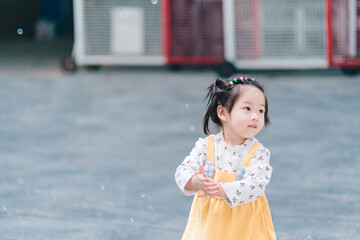 A cute happy little girl asian playing bubble outdoor.