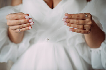 A miniature necklace in the hands of a bride in a dress 4404.