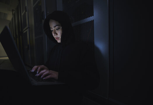 Hacking, server room and woman computer coding, data center crime and ransomware of cyberpunk in dark. Laptop hacker, person or thief in cybersecurity, information technology and criminal programmer