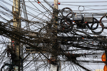 Communication and power transmission cables are seen attached to a street pole in central Bangkok,...