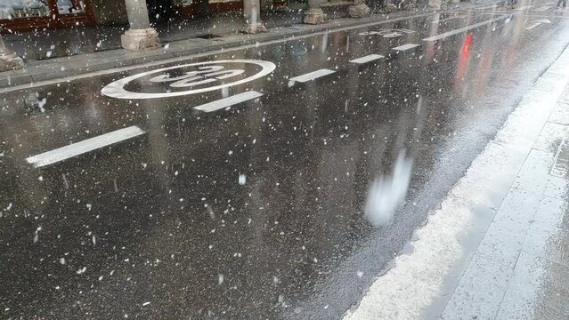 Copos de nieve caen sobre el asfalto de una calle en la ciudad de Valladolid durante el invierno, España