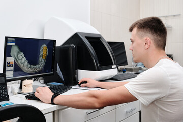 Dental technician working with a computer in a laboratory. 3D modeling of the crown in the dental lab - obrazy, fototapety, plakaty