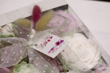 Homemade marshmallows in a cardboard box. Zephyr flowers. Gift wrap. Tied with ribbon. Close-up.