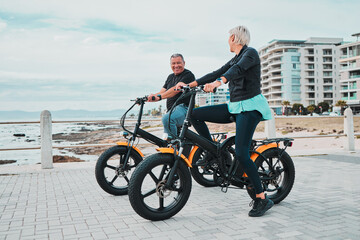 Mature couple, electrical and bike by ocean, beach or sea in bonding transportation, clean energy...