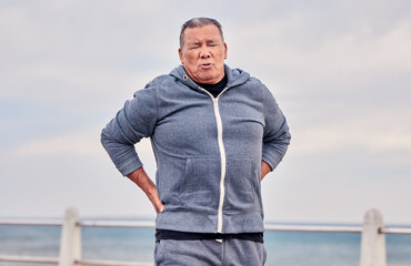 Back pain, fitness and senior man outdoor at beach with scoliosis, sports wound and risk. Male runner, spine injury and joint problem of body muscle, first aid and health emergency at ocean promenade