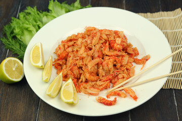 boiled craw fish meat on the plate with lemon slices, Japanese sticks, salad and straw mat closeup photo