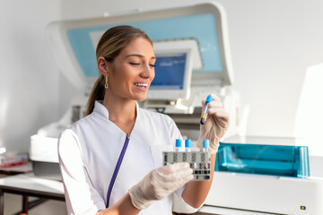 Fototapeta premium Laboratory assistant putting test tubes into the holder. Scientist doctor looking at blood test tube working at biochemistry experiment in microbiology hospital laboratory.