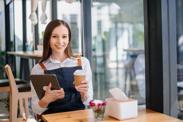 Woman coffee shop owner holding  notepad and digital tablet ready to receive orders.  in cafe restaurant. woman barista cafe .