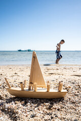 Happy vacation, boy toy boat beach, kid playing with wood toy boat, beach view
