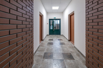 white empty long corridor with red brick walls for room office in interior of modern apartments, office or clinic