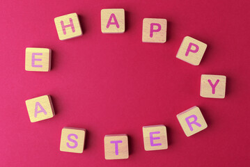 Wooden blocks arranged in egg shape with lettering Happy Easter on viva magenta background. Easter holiday concept