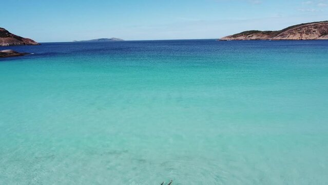 Aerial video of a person swimming in the transparent water of Cape le grand national park in Esperance, Australia. Dip into Hellfire Bay blue water. Drone view of the ocean and water.