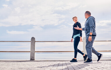 Walking, fitness and senior couple talking by ocean for exercise, healthy body and wellness in retirement. Sports, nature and elderly man and woman for warm up, cardio workout and training outdoors
