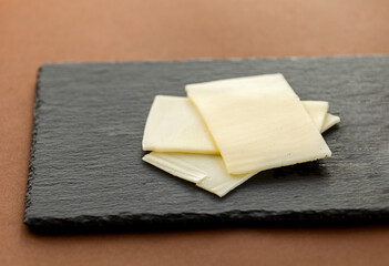 close up cheese on black stone board at brown background