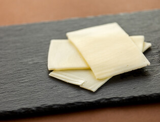 close up cheese on black stone board at brown background