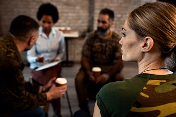 Group of diverse veterans talking during PTSD support group.