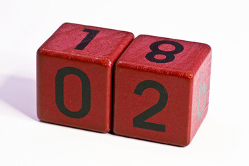 Number two and eighteen written on a red wooden cube of a calendar date
