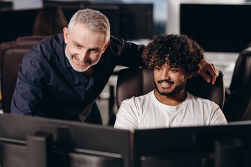 Job mentor checking new employee task. Smiling supervisor and trainee guy looking at monitor in...