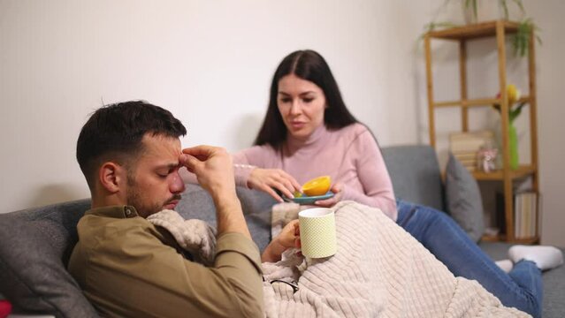 Sick young couple drinking hot tea at home - health, flu and people concept