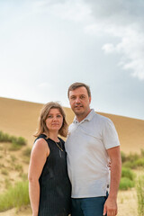Happy hugging couple on sand dunes looking at camera