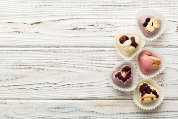 chocolate sweets in the form of a heart with fruits and nuts on a colored background. top view with space for text, holiday concept