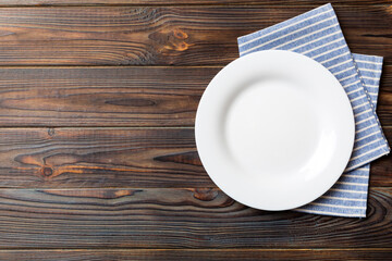 Top view on colored background empty round white plate on tablecloth for food. Empty dish on napkin with space for your design