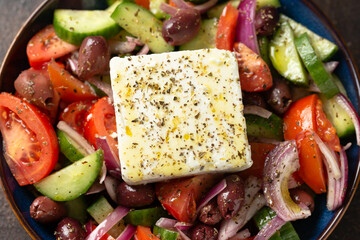 Fresh greek salad with tomato, cucumber, bel pepper , olives and feta cheese on black plate, top...