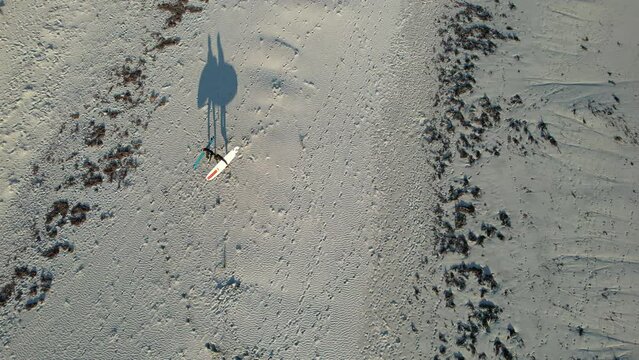 Aerial video of two surfers going out of the water after a surf session. Shadow of surfboards and surfers walking on the beach. Top down drone footage of a surf beach in Western Australia.