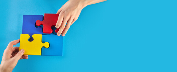 Father and autistic son hands holding jigsaw puzzle shape. World Autism Awareness Day