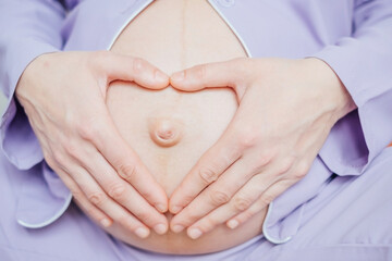 Close-up of pregnant woman keeping her hands on belly.