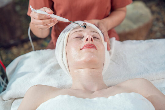 Young beautiful caucasian lying at spa facial masseuse hands use guasa wood to reduce wrinkles to help freshen and moisturize skin in spa wellness