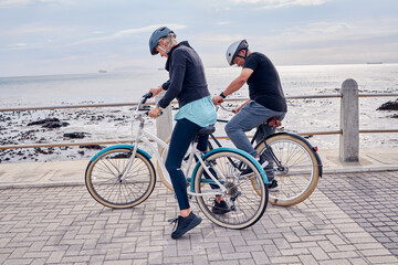 Bike, cycling and fitness with a senior couple on the promenade, riding eco friendly transport for travel. Bicycle, beach or exercise with a mature man and woman cyclist out on a ride for tourism