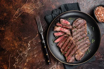 Tuinposter Barbecue denver strip beef meat steak on a plate. Dark background. Top view. Copy space © Vladimir